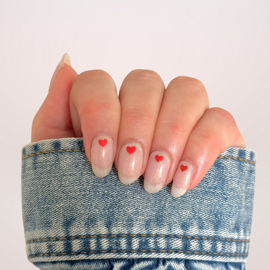 Semi-transparante witte gellakstickers met subtiele glitter en een klein rood hartje