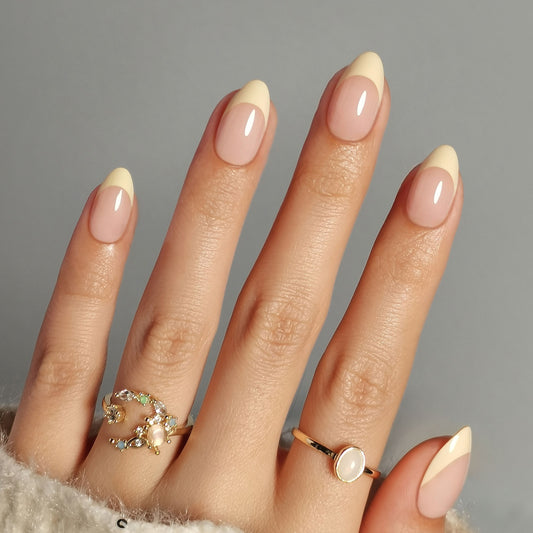 Butter yellow French press-on nagels in almond vorm met een natuurlijke nude basis en zachte botergele French tip