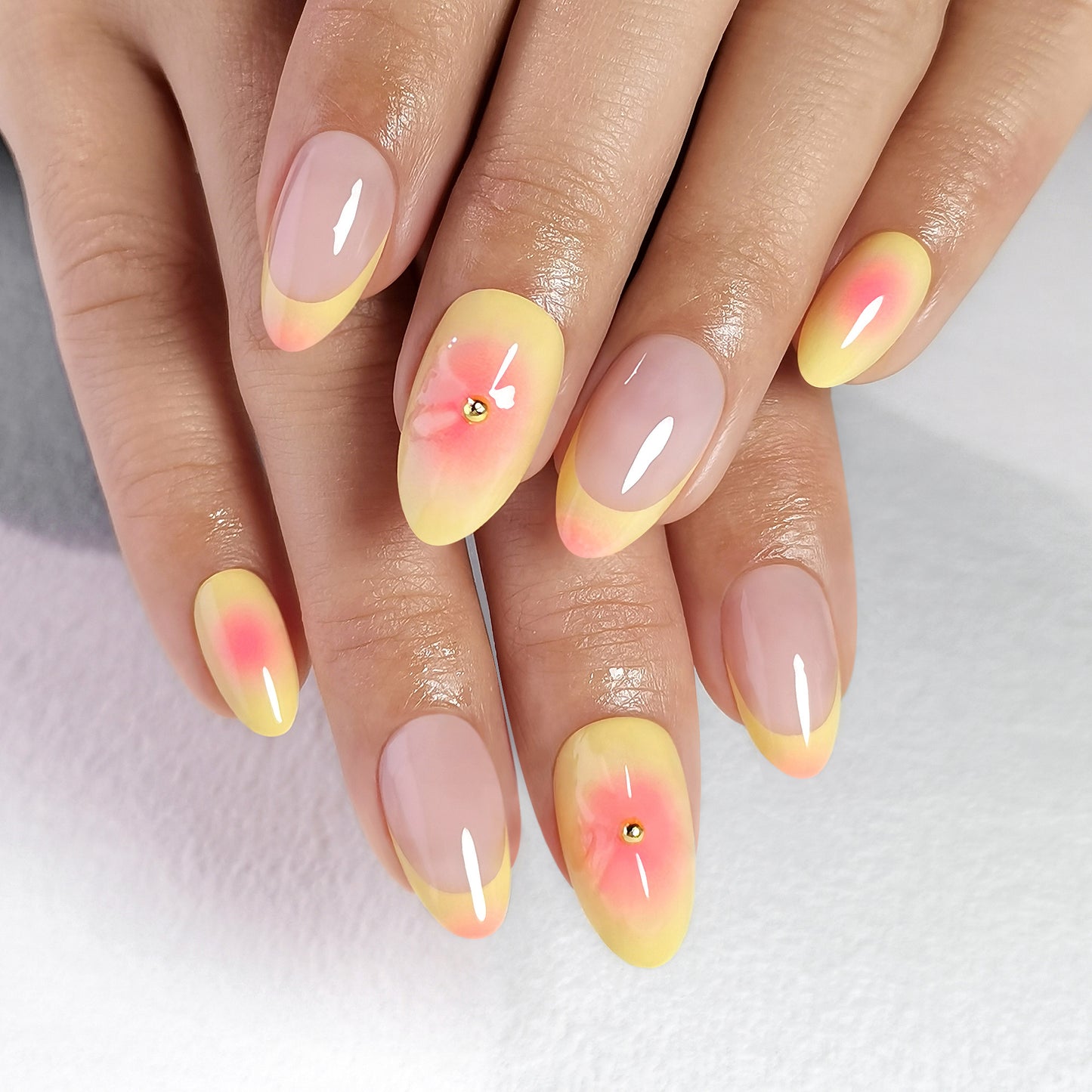 Butter Yellow gele soft gel press-on nagels met perzikkleurige accenten, bloemendesign en nude basis in almond vorm