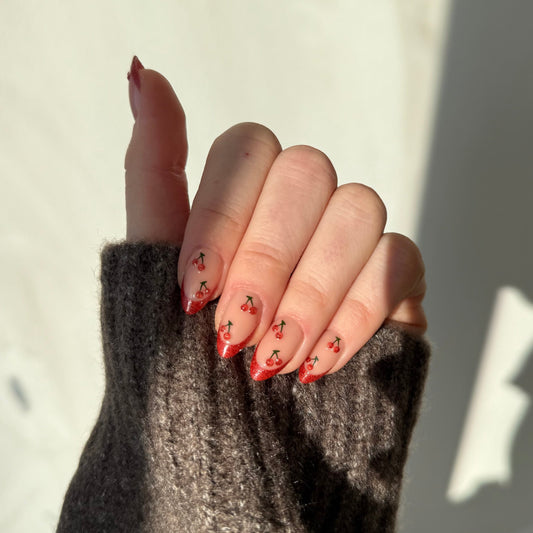 Rode French manicure en op de basis op elke nagel twee kersen. Al het rode heeft een subtiele glitter welke vooral in de zon zichtbaar is