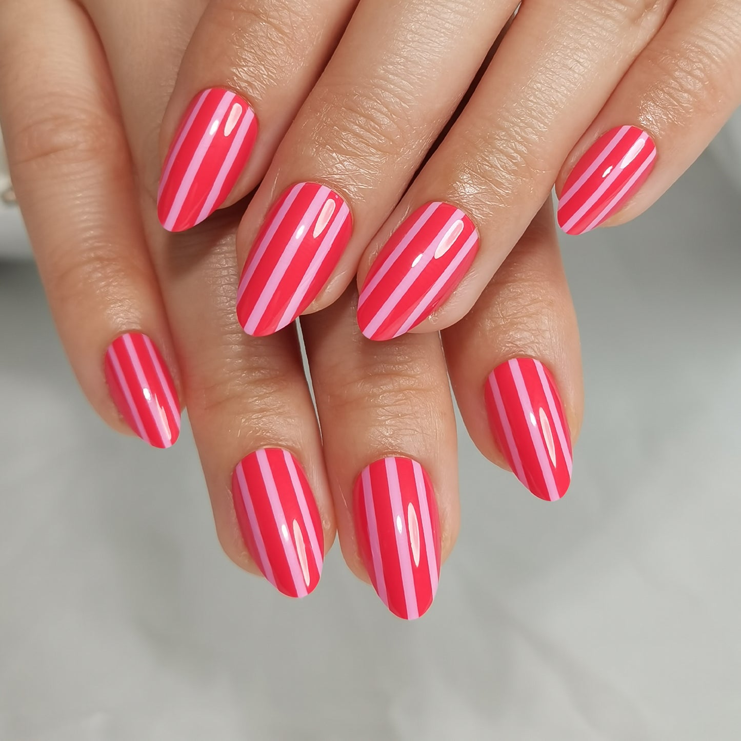 Roze gestreepte soft gel press-on nagels in almond vorm met neonroze en lichtroze verticale strepen.