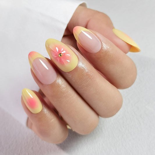 Butter Yellow gele soft gel press-on nagels met perzikkleurige accenten, bloemendesign en nude basis in almond vorm